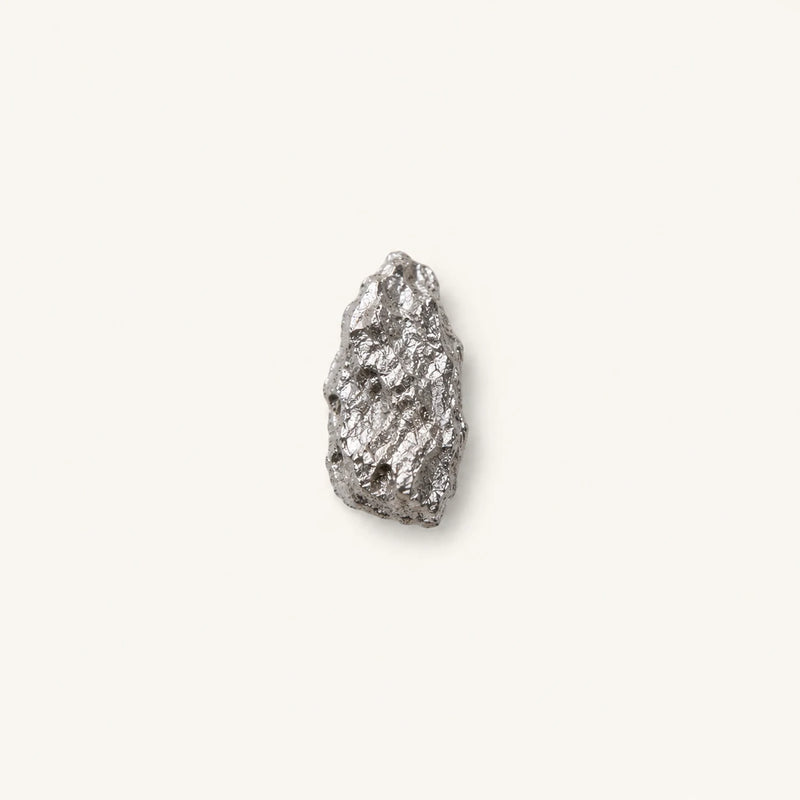 A single piece of magnesium citrate, centered on a solid off-white background.
