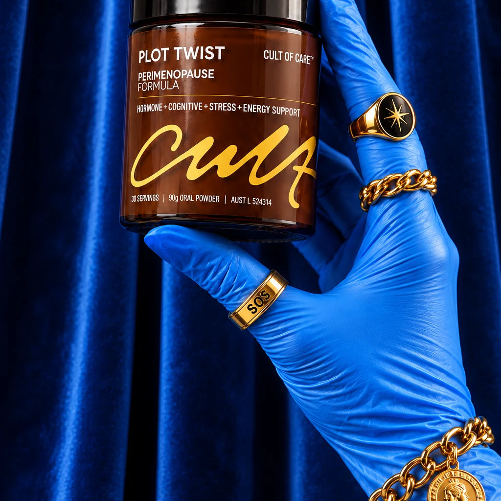 A hand wearing a bright blue surgical glove holds a jar of Cult of Care Plot Twist Perimenopause Formula in front of a draped blue velvet background. The hand is adorned with multiple gold rings and bracelets.
