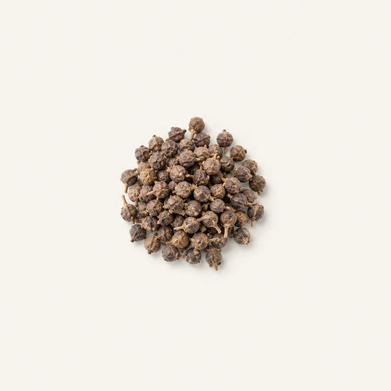 A small pile of dried Vitex agnus-castus centered on a plain off-white background.