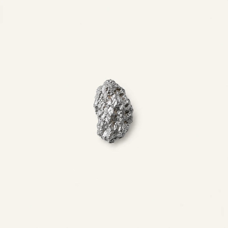 A small piece of Zinc glycinate centered on a solid off-white background.
